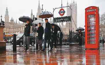  英国伦敦街头，雨中的撑伞者成为风景线 